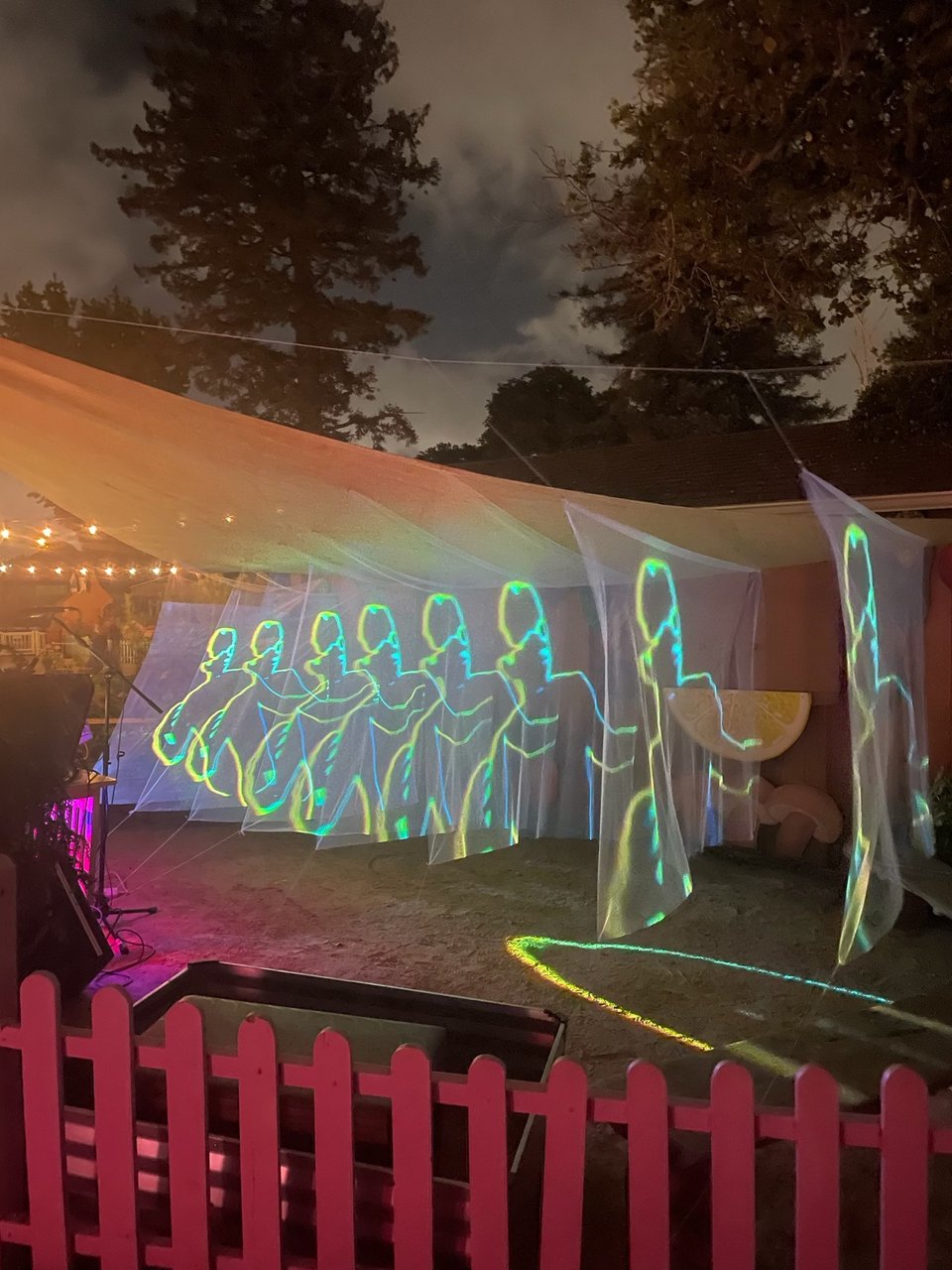 A neon outline of a person is projected across many thin sheets of netting. The installation, called "Already Still Again," was shown at the Oakland music and arts festival Through the Looking Glass on September 16, 2023.