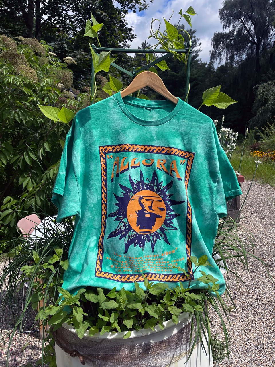 an ALLORA t-shirt hanging out in a barrel of herbs