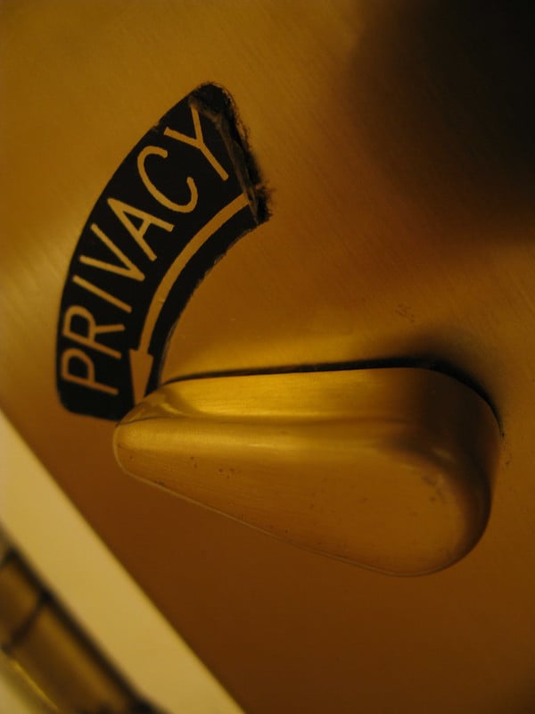 An angled photograph of a bathroom door, with the lock switch toggled to "privacy."