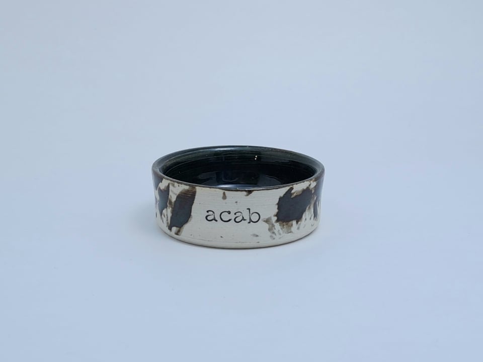 Tiny ceramic tray stamped with "acab"