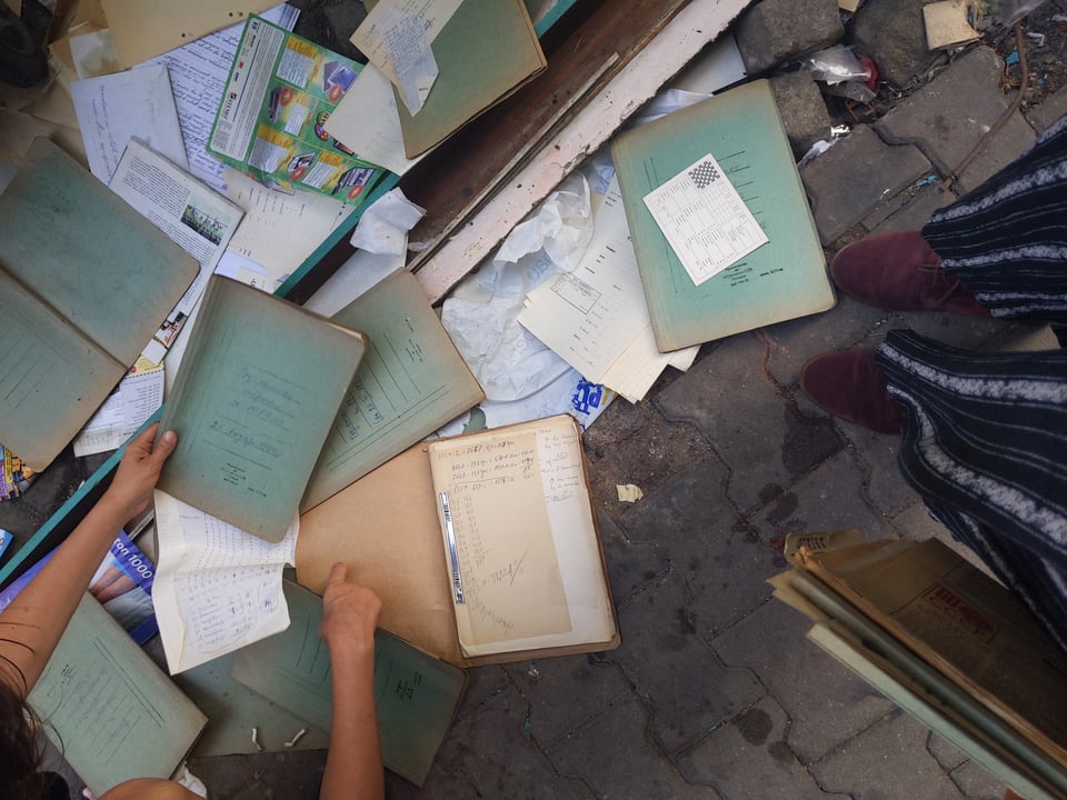 [Papers and faded green folders spread out on concrete.]