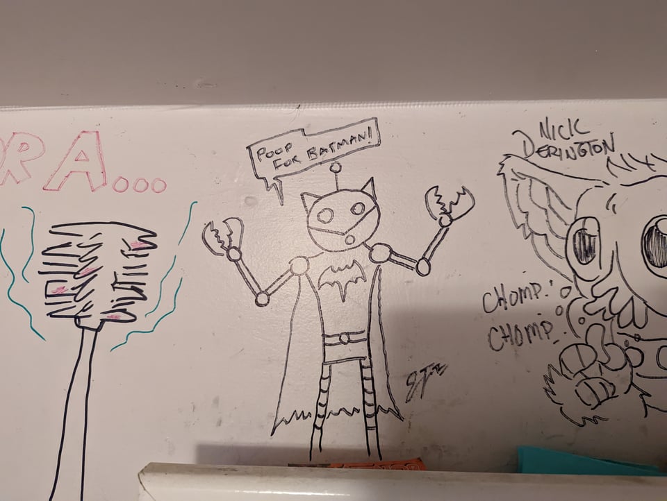 Bathroom grafitti shows a robot Batman with pincer claws saying POOP FOR BATMAN!