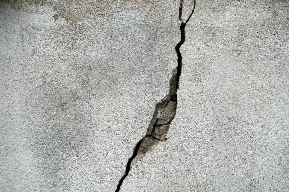 A closeup of a concrete wall with a large crack running vertically down the center