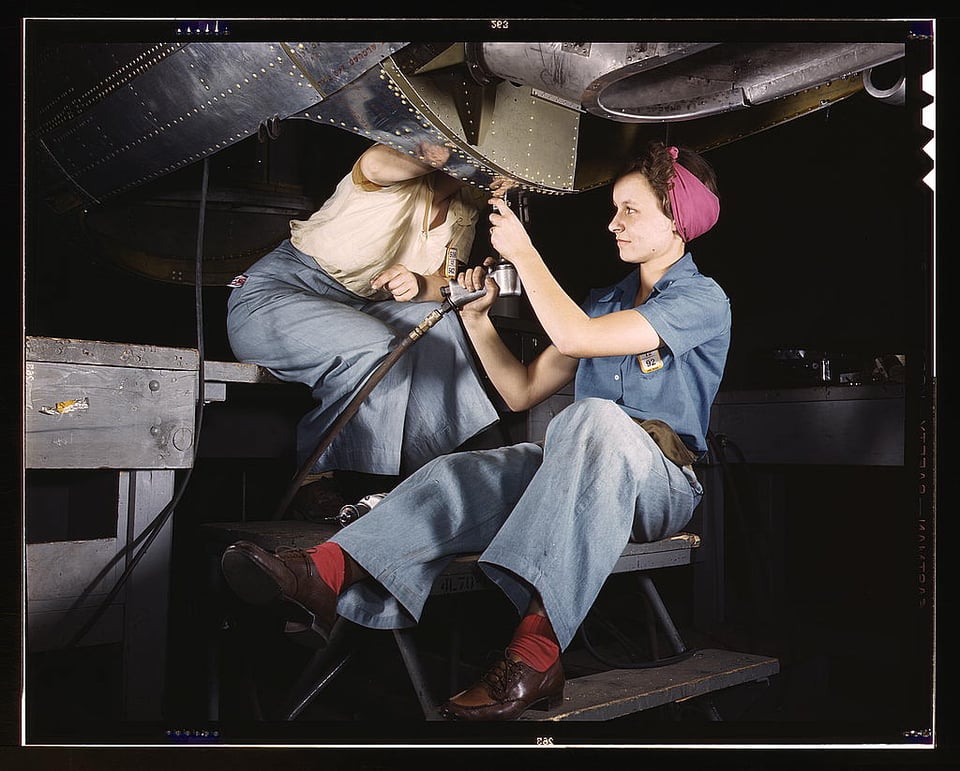 Two women fix an aircraft, possibly during the war.