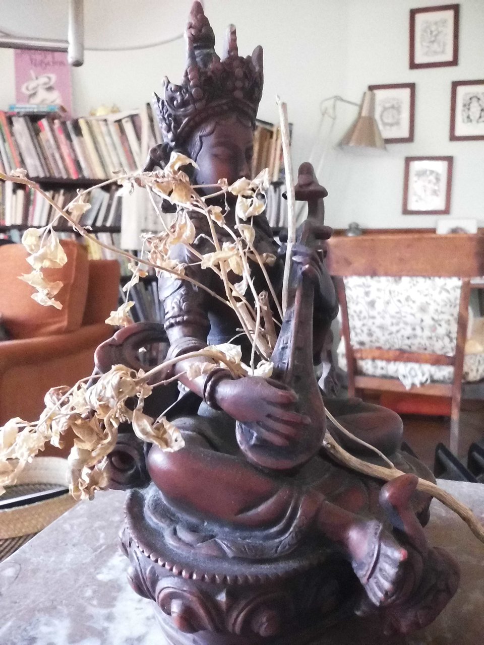 digital Instax photo of a wooden sculpture of Saraswati, a Hindu god playing a lyre