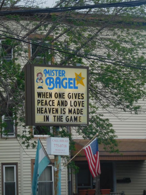 a reader board style Mister Bagel sign, which reads, "when one gives peace and love heaven is made in the game"