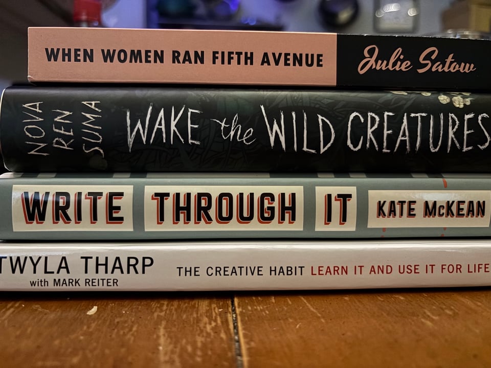 a stack of books sitting on a wooden table (book titles in the paragraph below).