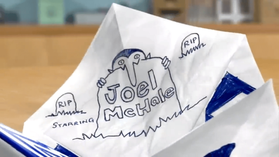 A paper fortune teller unfolds to read "Starring Joel McHale", with a drawing of a Dracula peering over a tombstone.