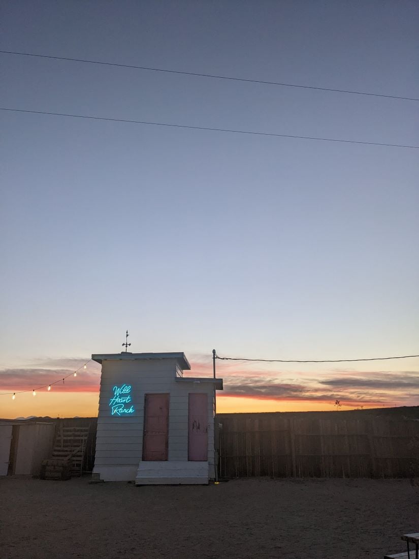A small out building in the desert while the sun sets.