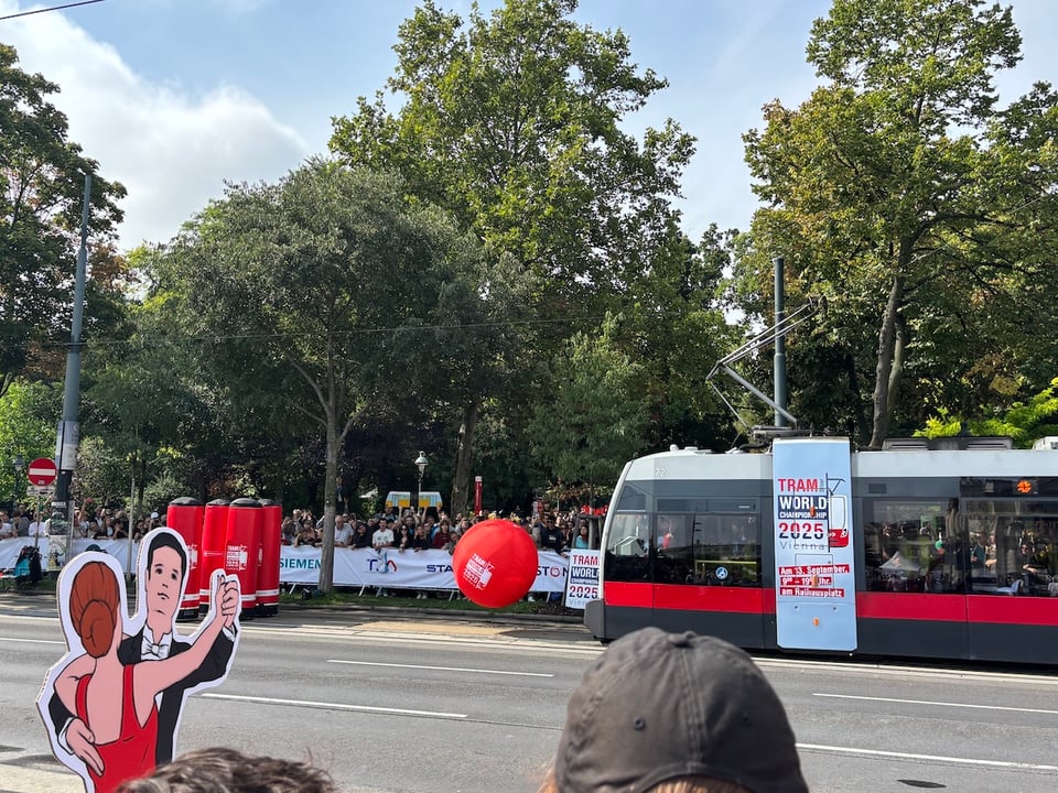 A tram has just hit a big (metre-high?) inflatable ball, which bounces towards five tall (two metres?) inflatable pins
