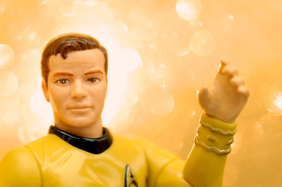 An action figure of Captain James T. Kirk from Star Trek, against a yellow background.