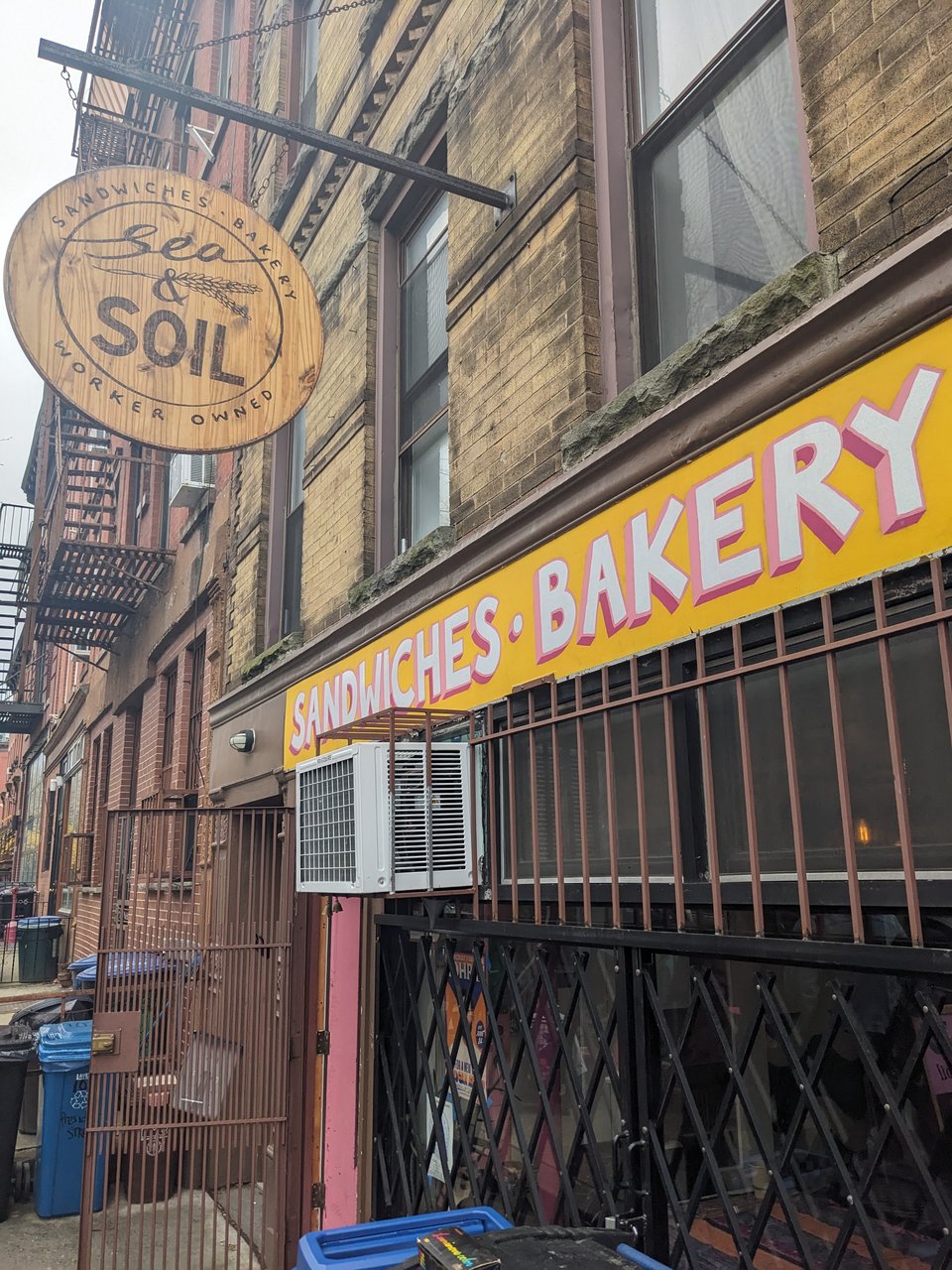 Sea and Soil's sign, above their storefront, covered by a set of grates.