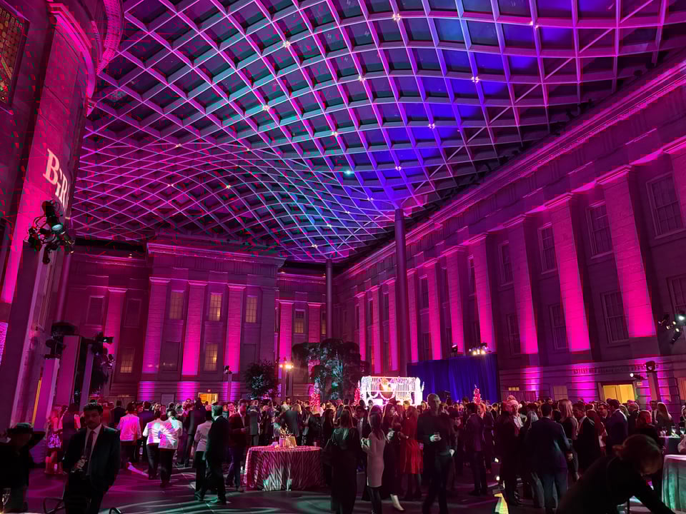 photo of interior atrium/quad of National Portrait Gallery in Washington, DC, w/lots of columns illuminated by purple lights, and an undulating lattice ceiling