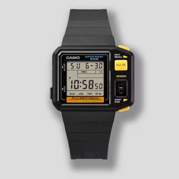 A Casio digital watch is shown with a square display and bold yellow accents highlighting its “Pulse” and “Sensor” buttons. The screen displays the day, date, and time along with smaller indicator icons for modes like alarm, jogging, and timer. Its black band and chunky design give it a rugged, sporty feel, emphasizing its built-in pulse-checking feature.