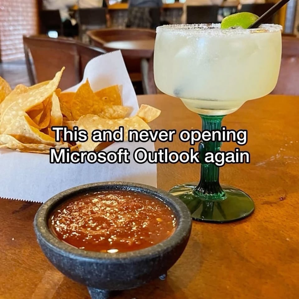 A restaurant table has a large margarita glass, a basket of tortilla chips and a stone bowl of red salsa. There is text "This and never opening Microsoft Outlook again".
