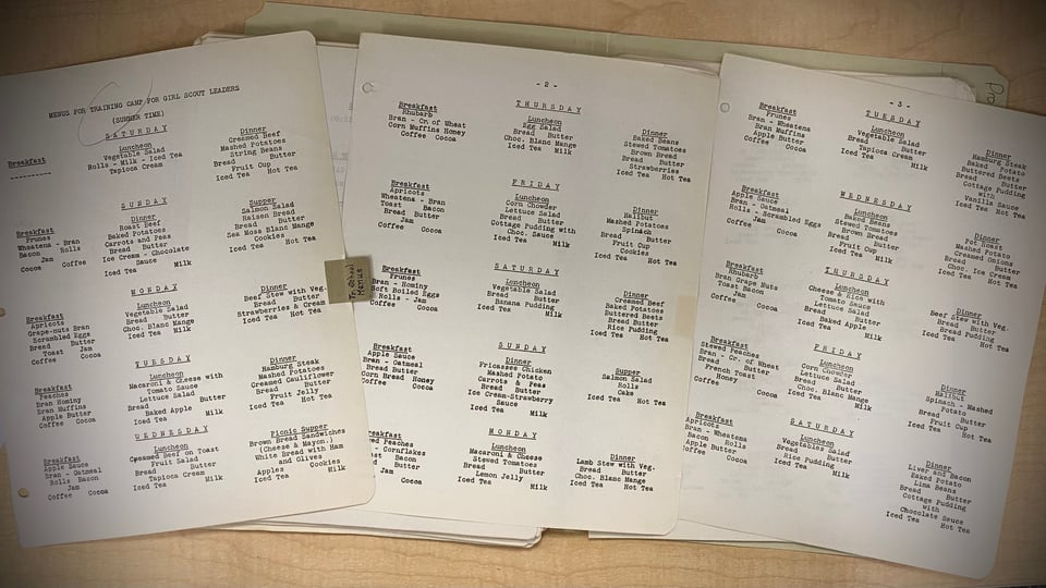 archival Girl Scouts papers on a desk that show menus from camp