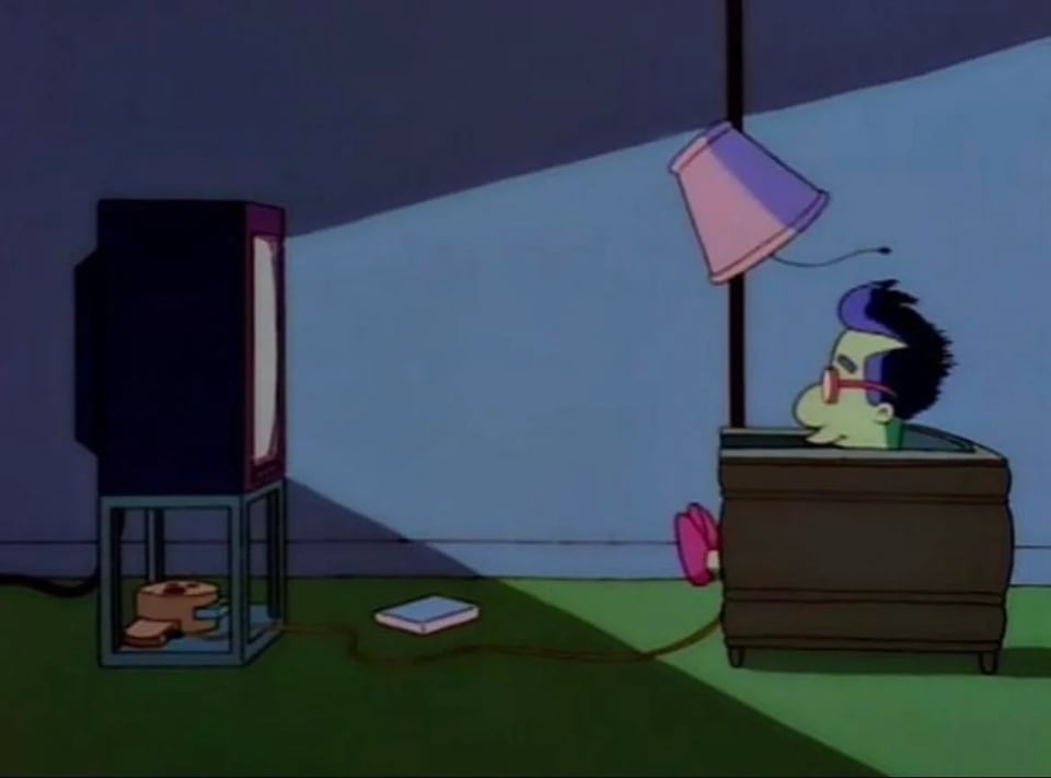 Millhouse from The Simpsons sitting in a chair playing the Bonestorm video game in the dark. He is smiling.