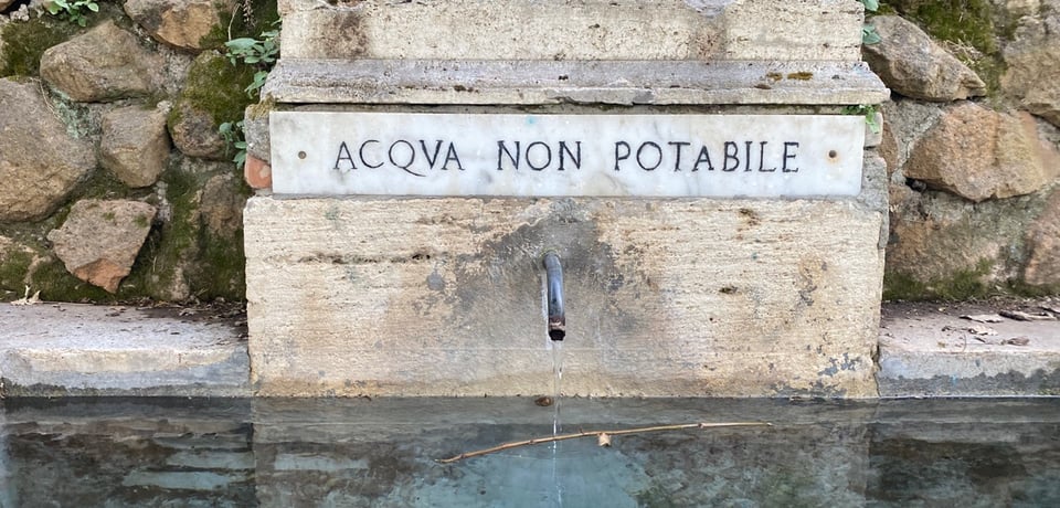 Water fountain in my local park with a carved sign that reads "Acqua non potable" the water is not drinkable.