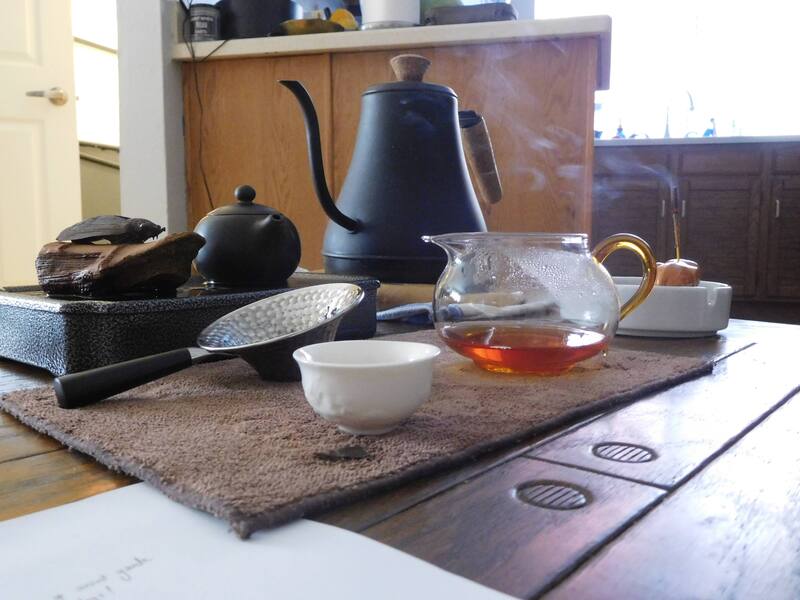 A kettle and tea set and a lit incense stick.