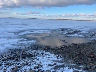 rocky Lake Michigan lakeshore, with a patch of cold water surrounded by ice