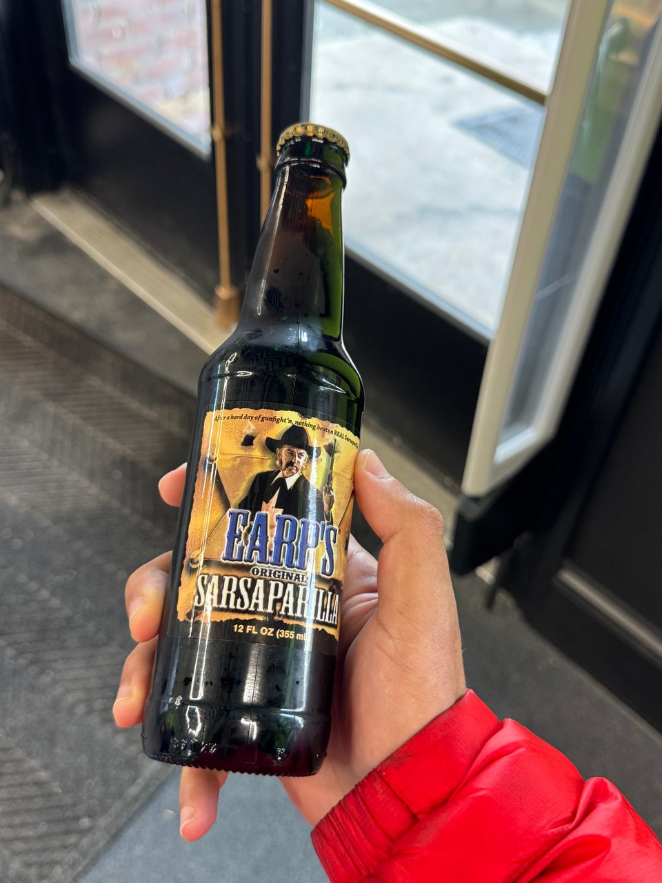 a bottle of Earp's Original Sarsaparilla. A gunslinging cowboy is on the label of the dark bottle.