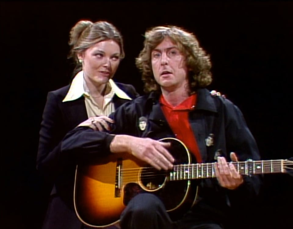 a man and woman holding an acoustic guitar
