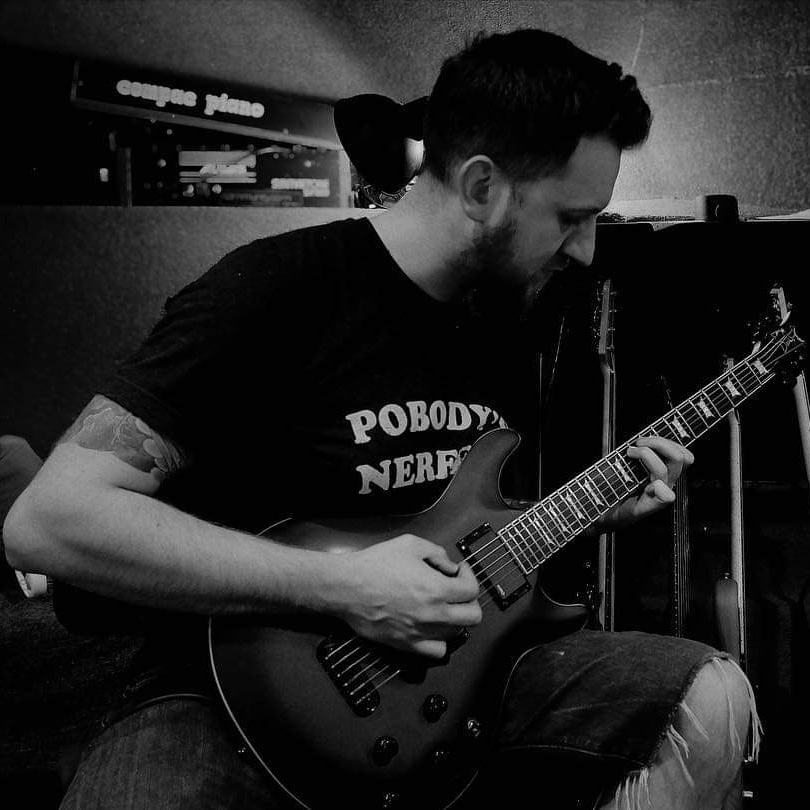 Chris playing his guitar in a recording studio