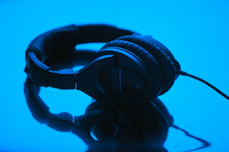 Description: a set of black over-the-ear Sennheiser headphones on a blue background. Photo by Patrick Fore on Unsplash