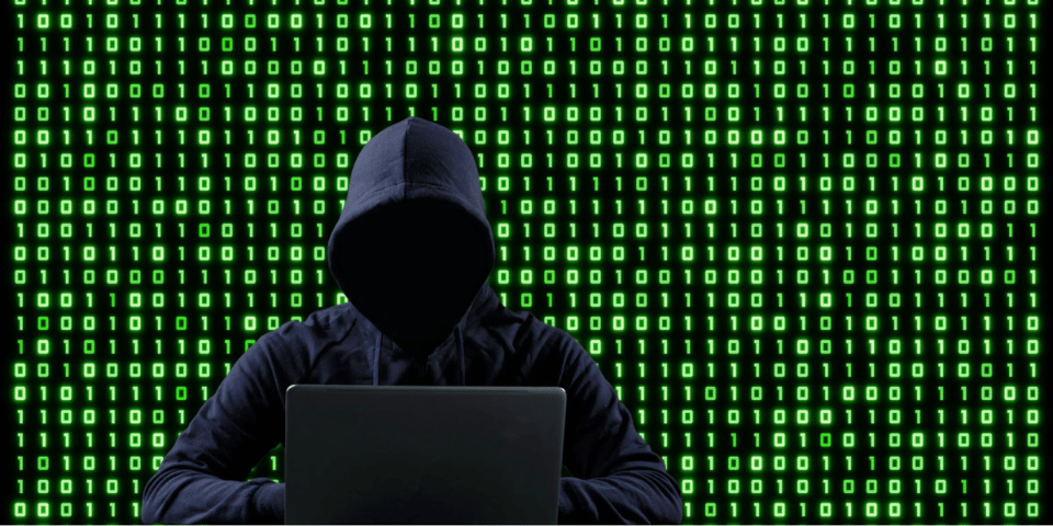 A hacker with a wall of green Matrix numbers behind.
