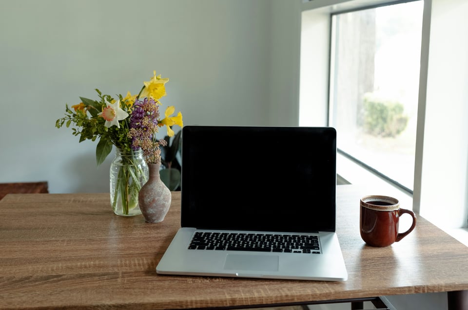 laptop and coffee cup and flowers in vase