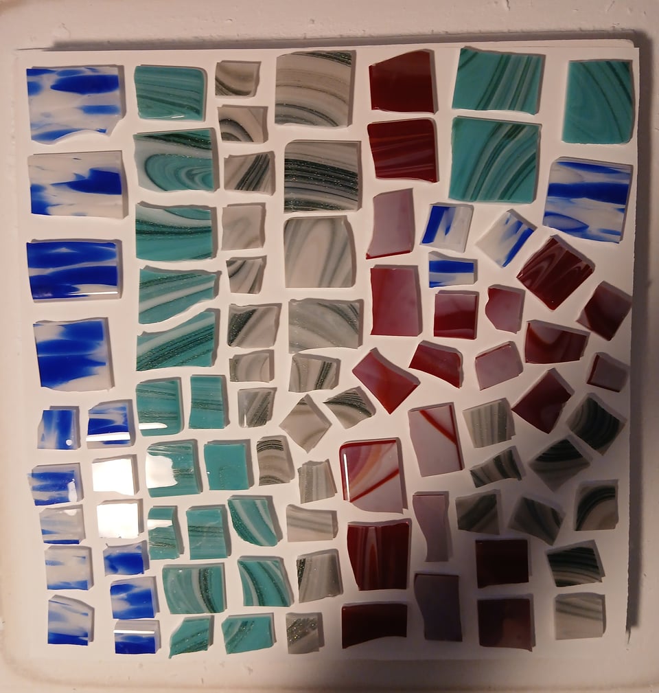 kiln shelf with glass pieces in blues, teams, greens and reds