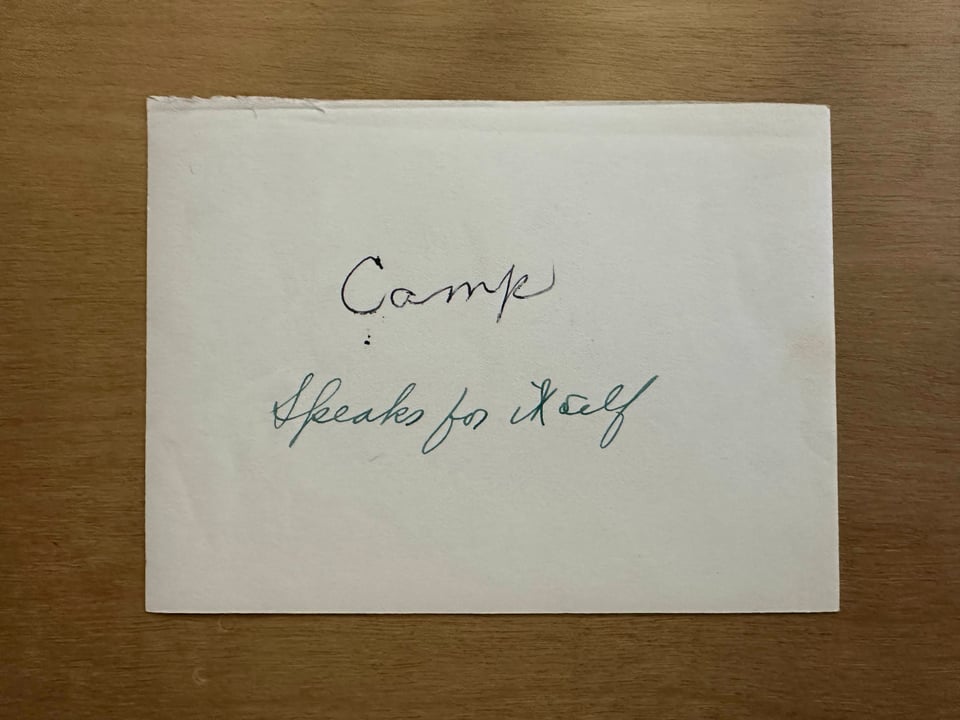 The back of the photograph with the word Camp written in black ink and then below it the phrase "Speaks for itself" written in green ink.