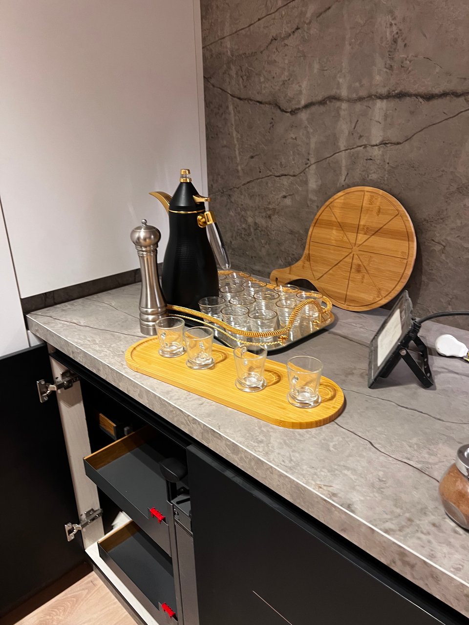 A coffee pot, a yellow tray, and glassware atop a sturdy and beautiful kitchen counter, with a backsplash that looks like (or is) granite