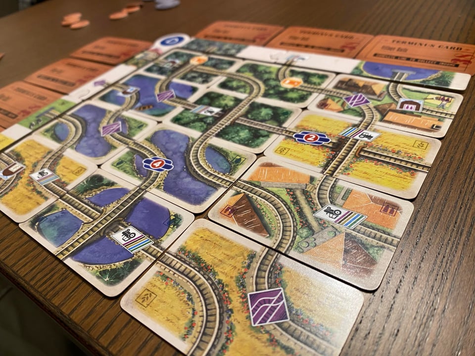 Mini cards arranged in a rectangle to create railroad tracks crossing various terrains.