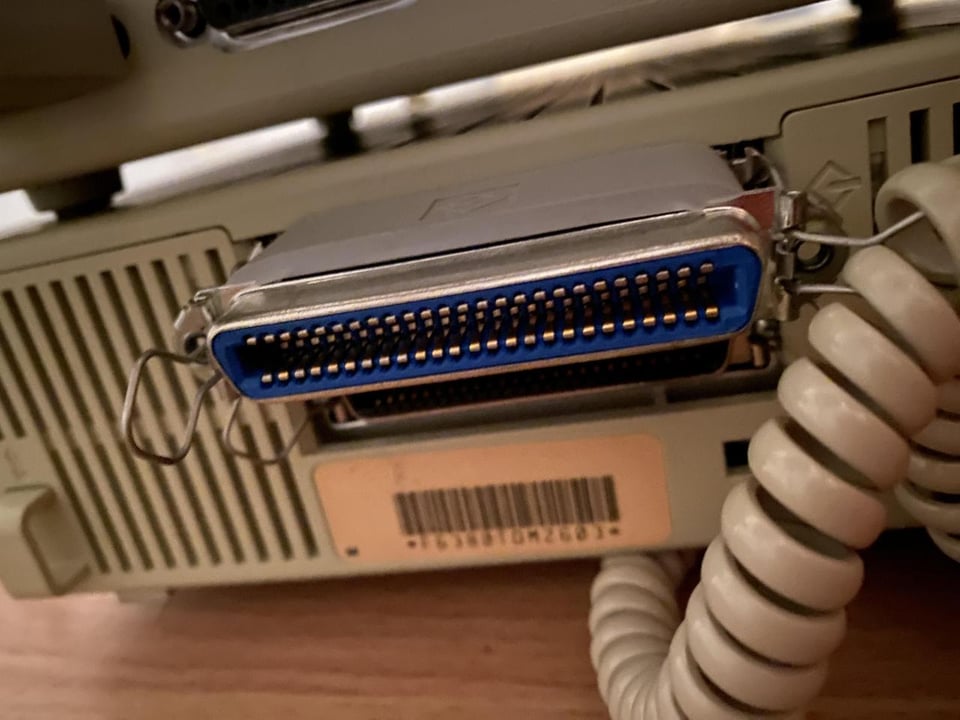 A photo of an old computer connector device, with a teethy circuit board jutting out next to a modem cable.