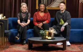 Three people sitting on a blue couch, smiling