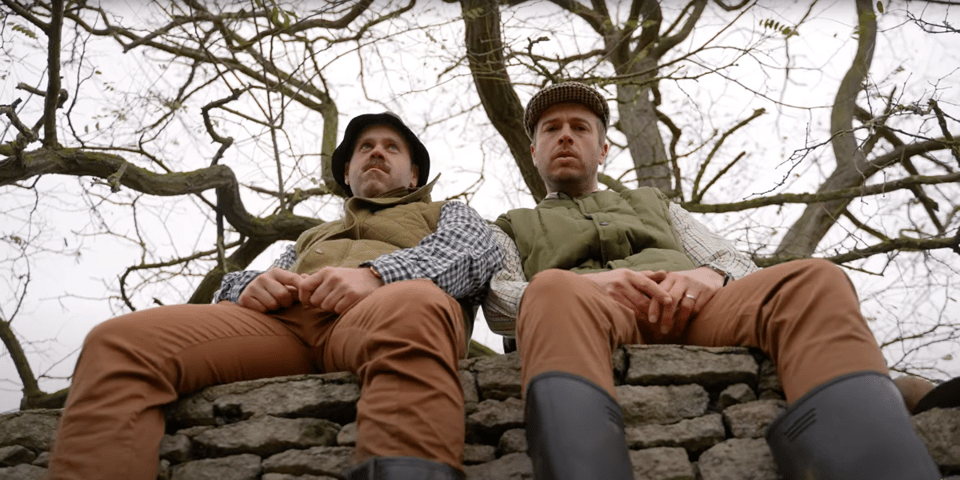 Two gangster farmers sit on a wall.
