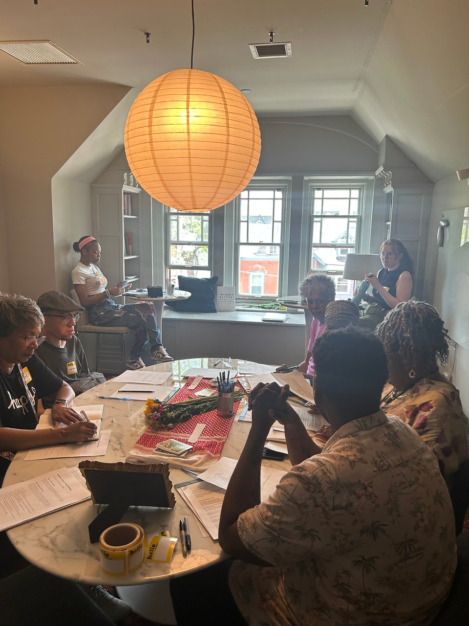 writing workshop participants gathered around a marble table writing on paper.
