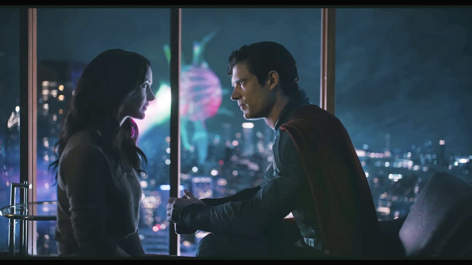 Lois and Superman look into each other's eyes - her more open, him a bit more reserved - as they sit down in an apartment, while through the window we can see some kind of glowing orb monster with tendrils blasting Metropolis with a laser beam.