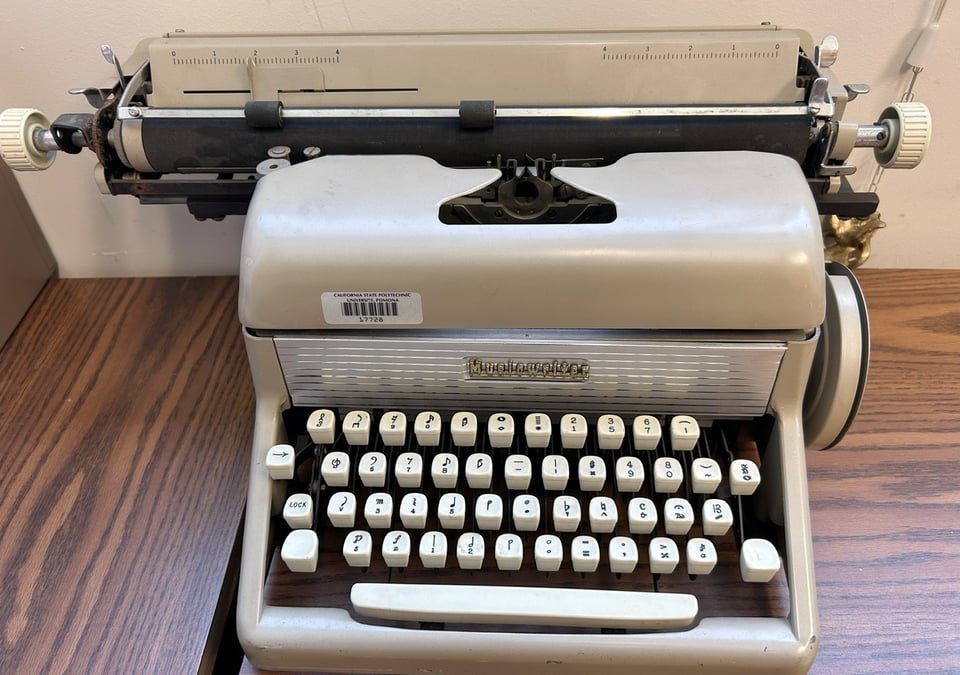 Mechanical typewriter with cream-colored chassis and keys. The keys have musical symbols printed on them.