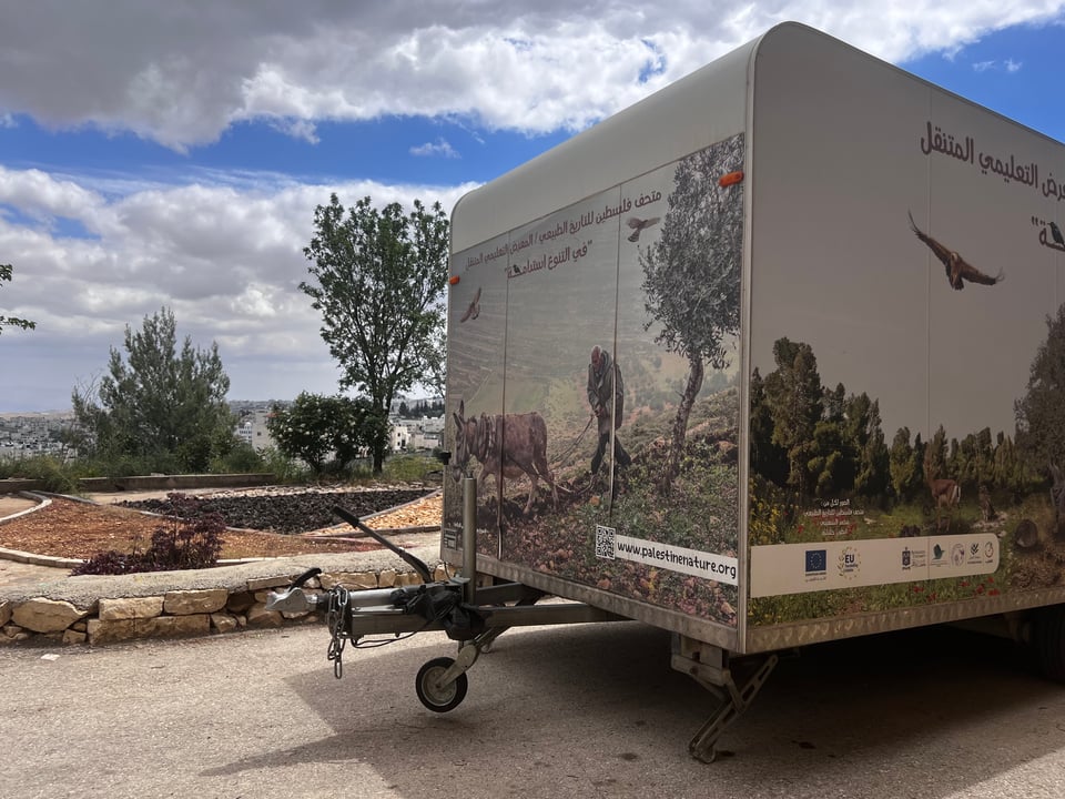 A trailer decorated with images of nature, Arabic writing, and www.palestinenature.org