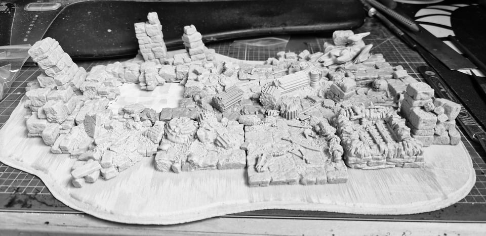 Black and white image of a ruined city diorama on a workshop desk.