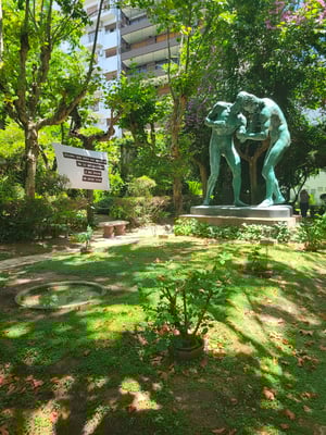 A garden with a large sculpture of two men wrestling.