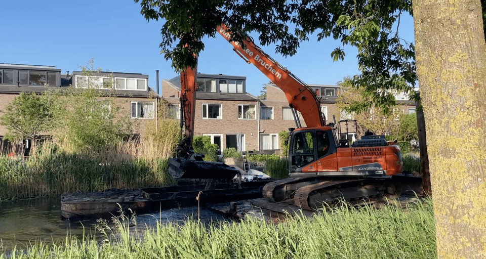 A floating digger dredges the canal of invasive plants.