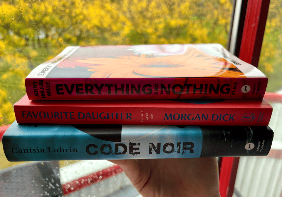 A little stack of books in front of some autumnal trees