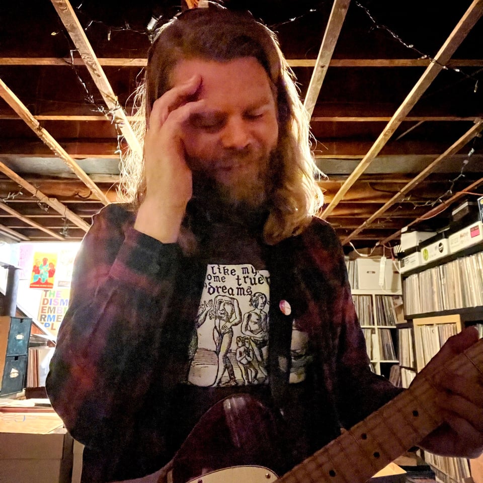Me holding a Telecaster with a hand to my temples, smiling. In my basement.