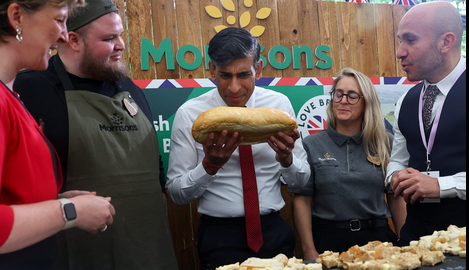 Rishi Sunak stares closely at a loaf of bread, frowning.