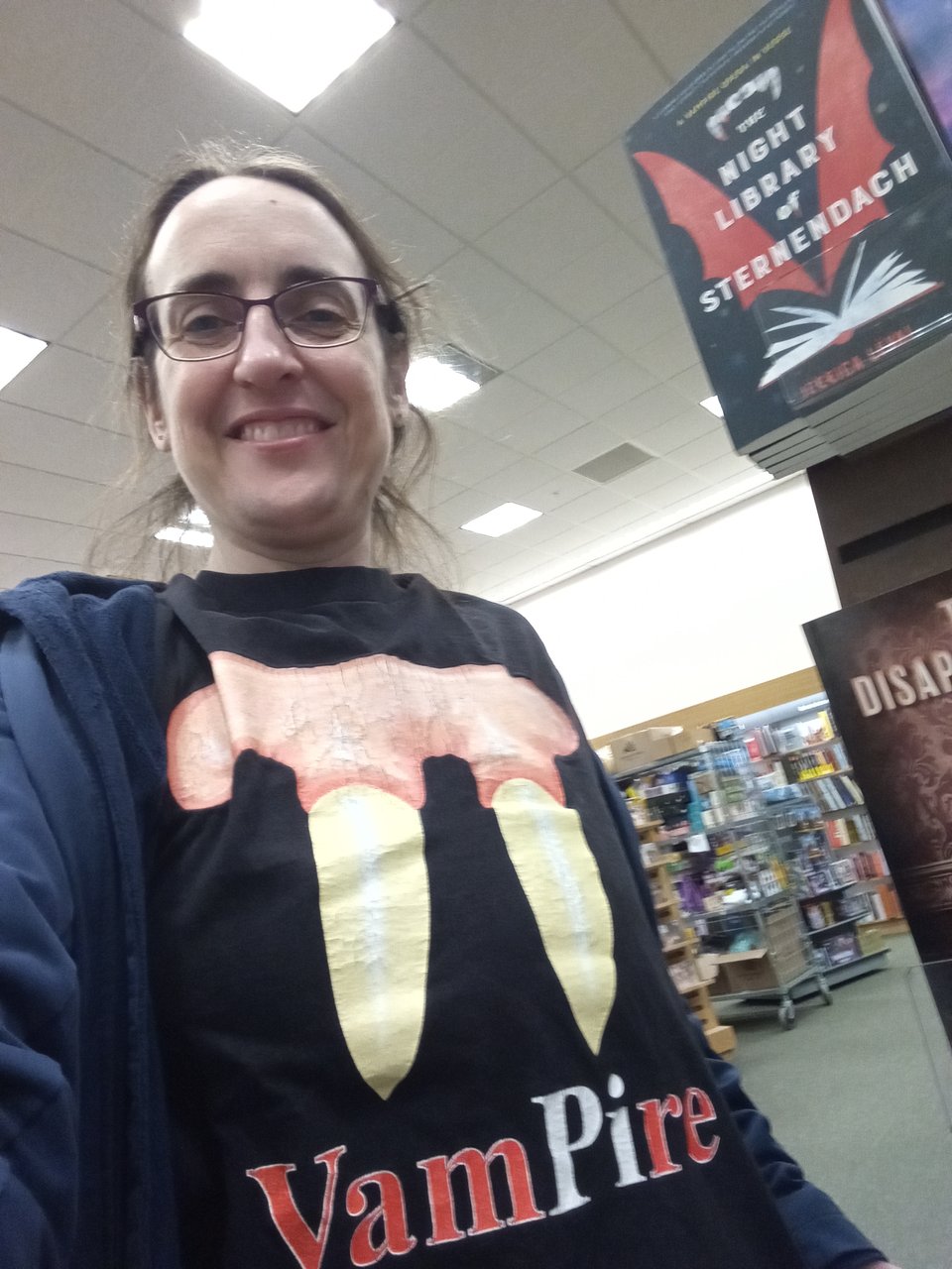 The author takes a selfie next to Sternendach at the local Barnes and Noble. She's wearing a tee shirt that says VamPIre and shows the greek letter pi as a pair of fangs.
