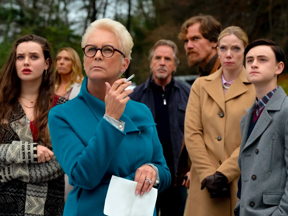 Some of the cast of the movie "Knives Out", with Jamie Lee Curtis in the front and center, wearing a blue jacket and smoking a cigarette