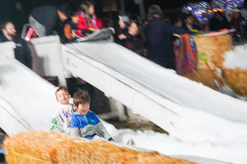 Two boys share a sled down a snow-covered slide